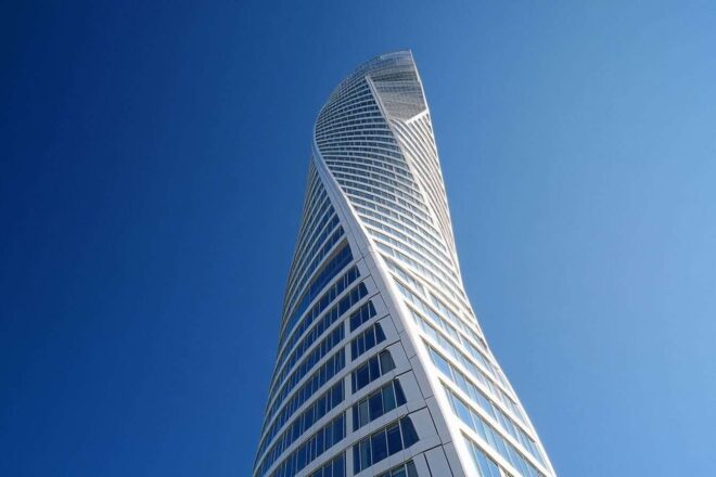 Une vue panoramique de l'emblématique gratte-ciel Turning Torso de Malmö sous un ciel bleu clair.