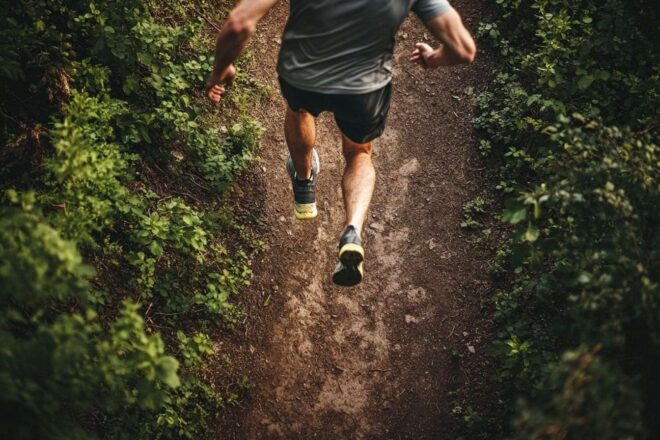 Un regard plongeant sur un athlète courant sur un chemin de terre, immortalisant l'harmonie avec la nature environnante.