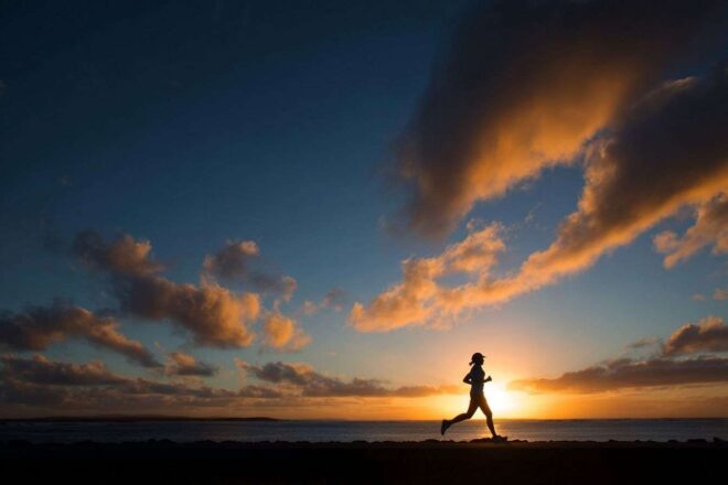 Vue panoramique de coureur en mouvement au coucher du soleil