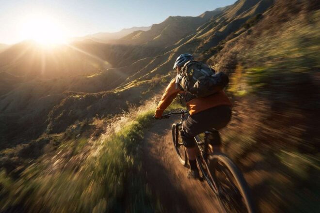Cycliste sur un sentier montagneux sinueux au lever du soleil