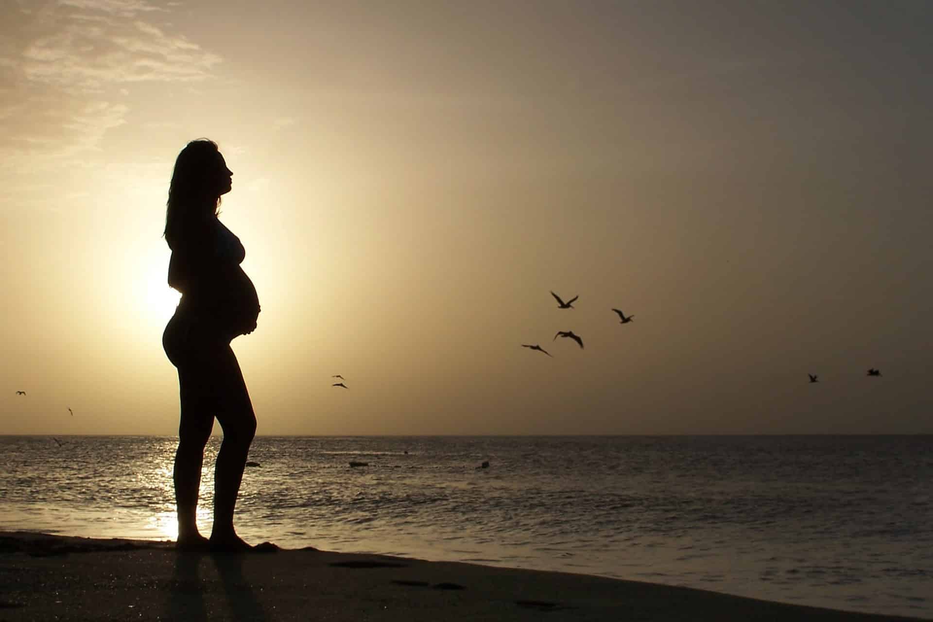 Une femme enceinte sur une plage.